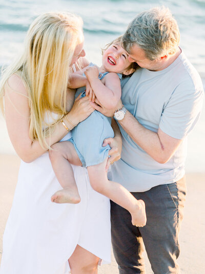 A mom and dad playing with their baby boy by the ocean in Ventura taken by Daniele Rose Photography