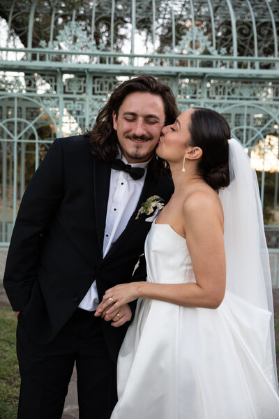 An Austin-based wedding photographer captures a tender moment of a bride and groom kissing in front of a gazebo.