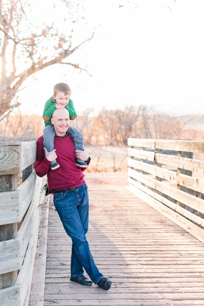 A father holds up his son on a bridge during winter in Colorado Springs by Laramee Love Photography
