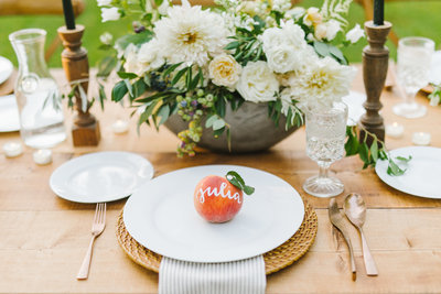 peach sitting on white plate in front of flowers