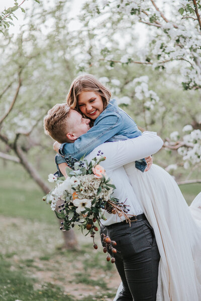 Sacramento Wedding Photographers capture groom lifting bride during almond blossom bridals