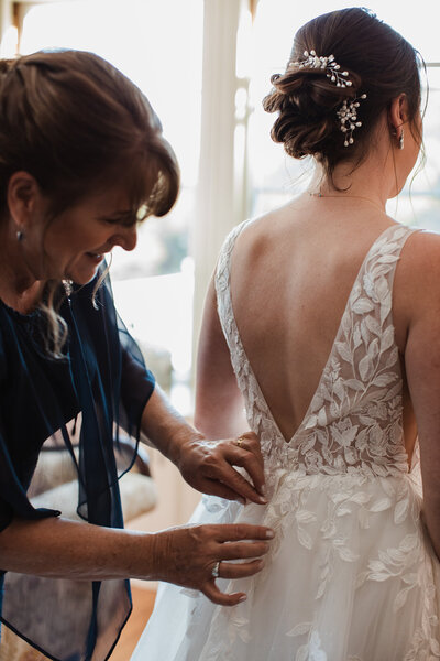 Mom helping bride zip on wedding dress at the Pierce house