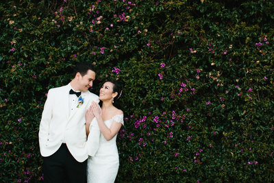 Bride and Groom smiling in front of green foliage at their Malibu wedding