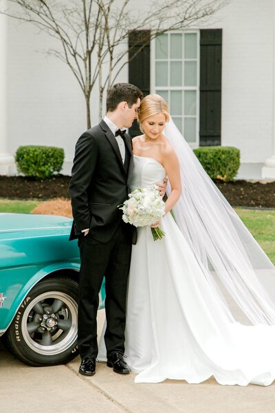 Bride and groom post with a classic car