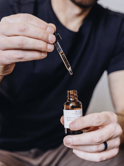 Person using a dropper to apply Primally Pure Beard Oil