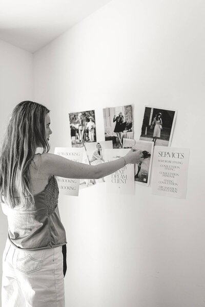 Branding photography capturing a business owner arranging visual concepts on a wall.