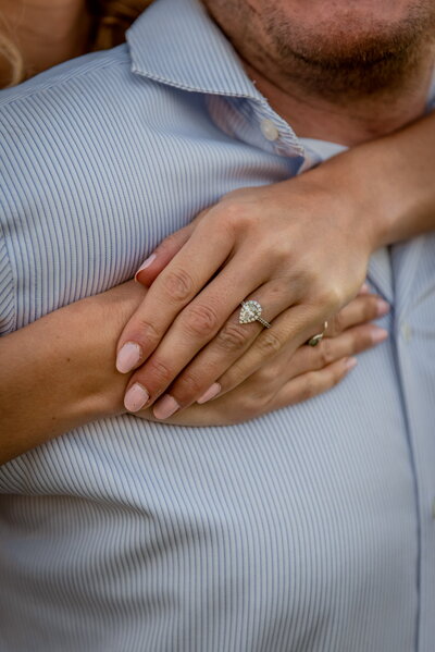 Close-up photo of a couple gently holding hands, showing an engagement ring during an intimate moment. Photographed by Sarah Ferrazzani Photography in New England.