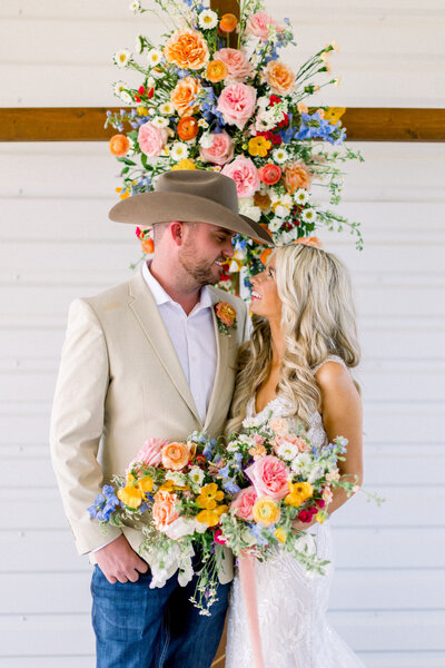 bride and groom taking photo in front of a cross with beautiful spring flowers