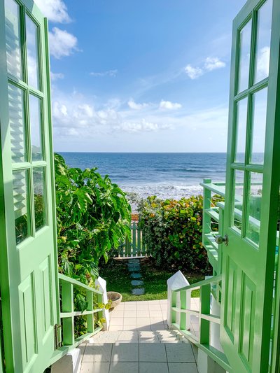 The view from Candice's favorite beach house, with green doors opening to a view of the caribbean sean