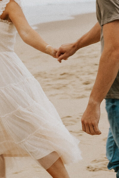 bride and groom running on beach elopement day