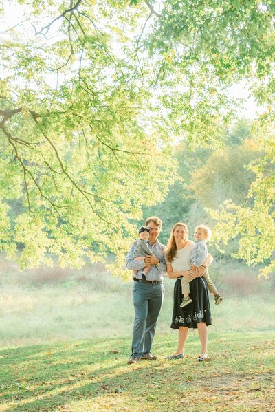 Family of four under tree canopy in the early fall woods by Chicago family photographer Kristen Hazelton
