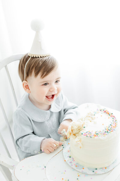 One year old baby boy celebrates his first birthday with a cake smash portrait session