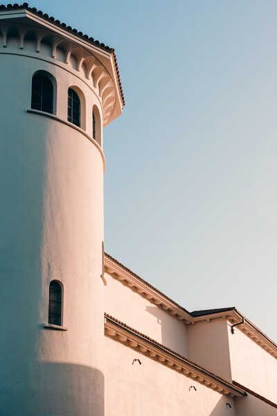 A white adobe tower stands contrasted by the sunset.