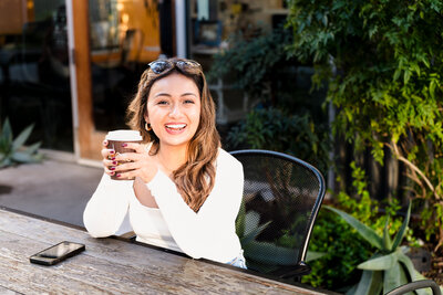 Woman in a coffee shop holding a coffee cup and smiling