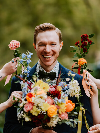 close up of groom with bouquets