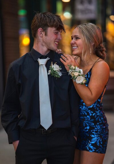 Young couple smiling at each other wearing flower corsage and boutonnière for prom
