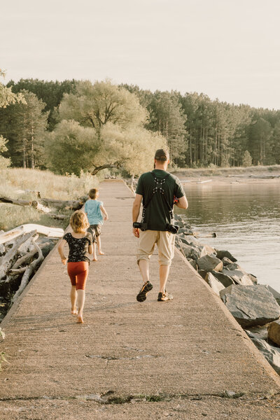 Dad and children walking on a boardwalk along a lake