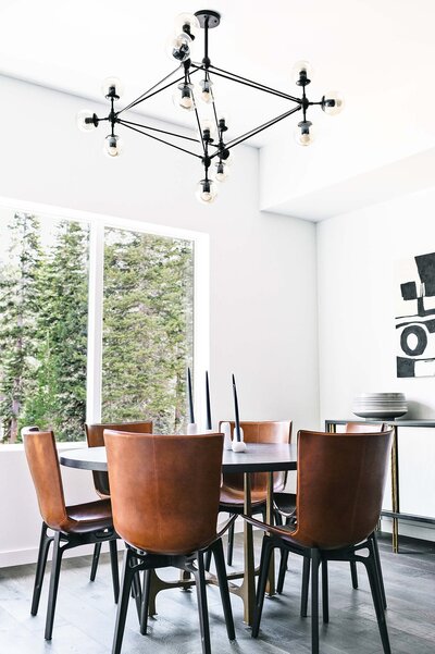 Interior of Palisades Tahoe condo showing dinner table and chairs with a brown leather and black and white decor. 