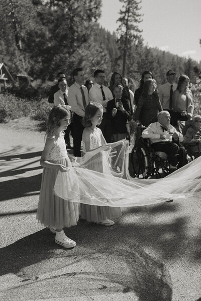flower girls holding the brides dress at a lake tahoe elopement