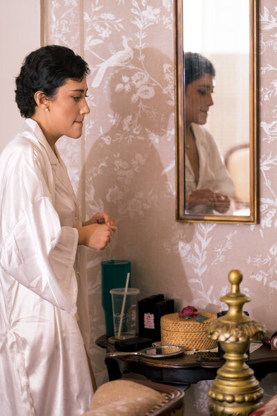 Bride getting ready by mirror in softly lit room before ceremony – photographed by wedding photographer Niko Coric – Lumen Clarity Media