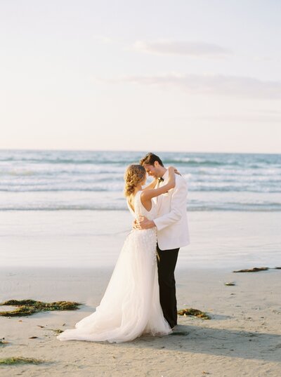 bride and groom standing on the beach
