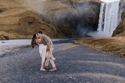 Iceland elopement photographer captures outdoor elopement of bride and groom kissing at waterfall