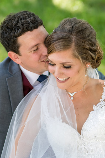 bride and groom laughing while he whispers in her ear