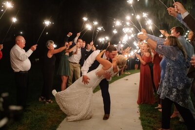 Groom dips bride for a kiss during a sparkler send off