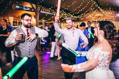 a bride and wedding guest dancing with light up foam wands