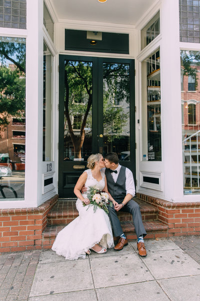 Bride and groom sit on steps of brick building downtown raleigh