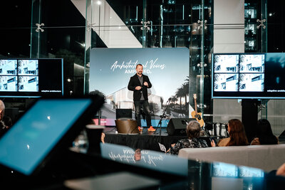 A man standing on a stage doing a presentation on architecture at the Teulo Architectural Event in Auckland captured by Zanthe Vorsatz, Auckland Event Photographer