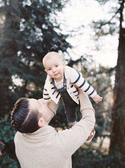 dad holds baby up in the air during family session