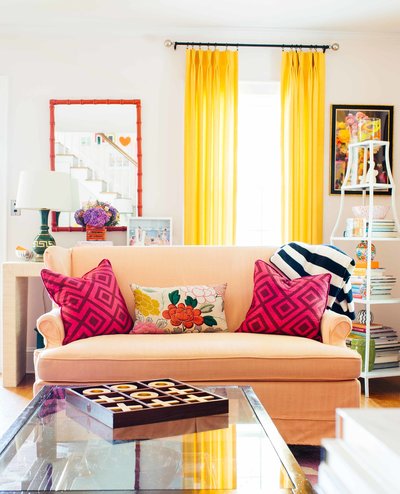 A peach sofa with bright pillows in colorfully decorated living room.