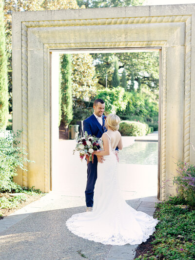 Bride and Groom smiling at each other under an archway