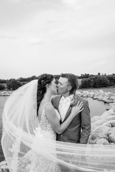 bride and groom kissing on their wedding day with veil flying in the wind by atlanta wedding photographers