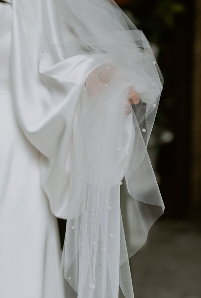 a Korean bride wearing a beaded white gown stands in a hanok