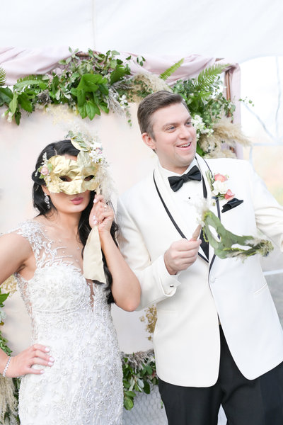 Bride and groom hold decorative masks