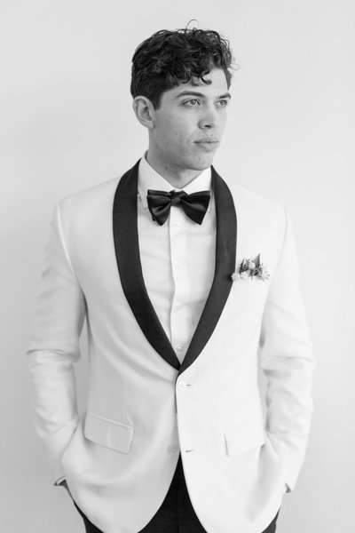 black and white photo of groom in white tux  by Colorado Wedding Photographer Kelby Maria