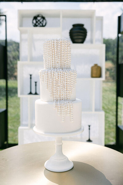 Get ready to indulge in a heavenly white wedding cake, crowned with elegant pearls that add a touch of sophistication and glamour