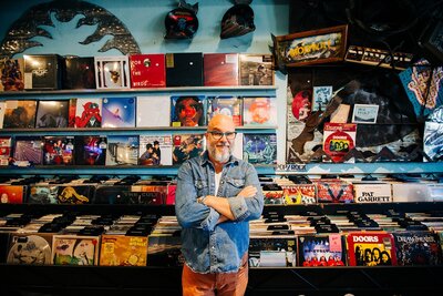 Owner of Perfect Sky wearing denim jacket standing in front of a record display