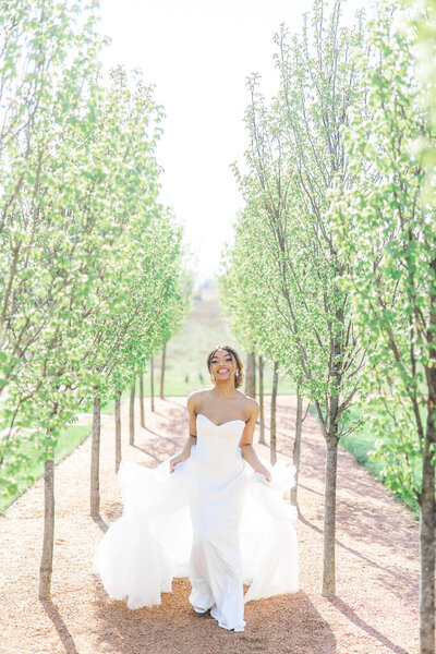 bride running through a line of trees outside magnolia hill farm in ohio