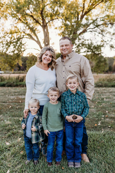 Parents and 3 boys smile for a picture while embracing the fall colors.