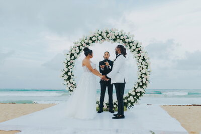 A bride and groom exchange vows on the beach.