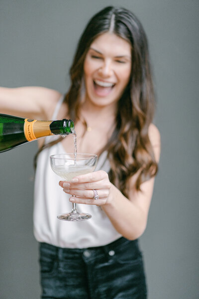 woman poring champagne into a glass for a toast