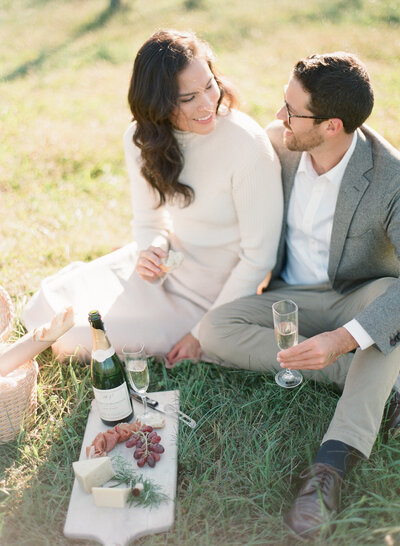 Engaged couple opens bottle of champagne during engagement portrait session