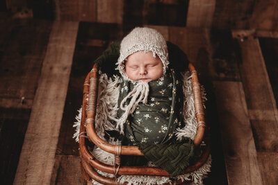 A baby snuggled in a wicker basket.