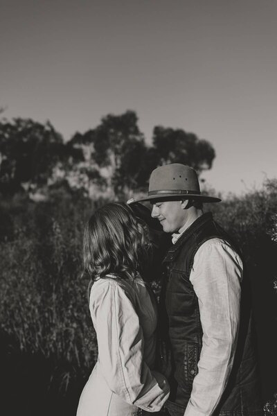 A tender moment between a couple during an engagement photoshoot in a rural field.