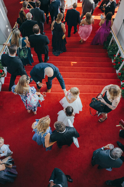 a top down view of wedding guests going down the red carpeted steps at the Grand Hotel