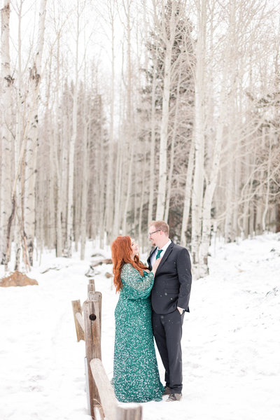 A redhead in a green dress during an engagement session in the snow
