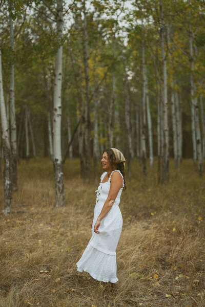 Emily Noelle, an Oregon eloepment photographer, wearing a white dress in the forest